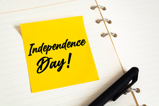 Closeup Yellow Sticky Note paste it in a notebook setting an appointment. The words Independence Day written on a white notebook to remind you an important appointment. - Powered by Adobe