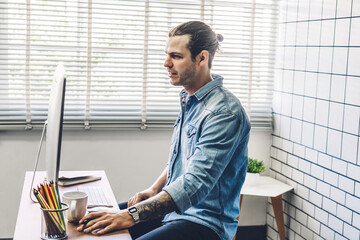 Handsome confident businessman relaxing looking at technology of desktop computer monitor while sitting on chair.Young creative coworkers business people working and typing on keyboard at office