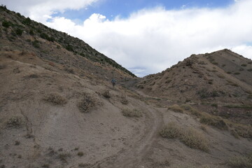 Distant cyclist riding mountain bike up steep dirt path