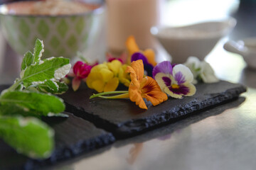fleurs mangeables sur une ardoise déposée sur un comptoir en acier inoxydable