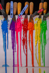 blue ,purple, pink, red,orange, yellow and green are slowly dripping from color scoop handle..and slowly spread onto the white paper.