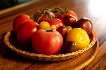 Fototapeta na wymiar bol en osier avec des tomates de toute sorte rouges et jaune ambiance chaleureuse