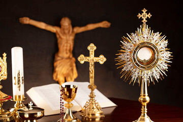 Religious holiday – Easter. Catholic symbols composition. Jesus figure, The Cross, monstrance,  Holy Bible, rosary and golden chalice on gray background. 