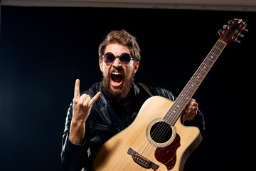 A man with a guitar in his hands leather jacket music performance rock star modern style dark background