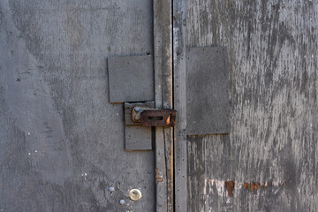 old plywood door with rusty metal latch without padlock