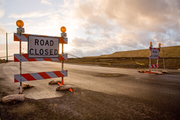 Closed road signs on an empty and deserted  road with bleak sky