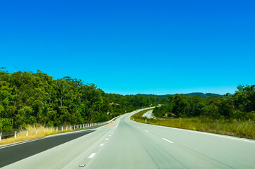 View of a long curved section of the newly opened Pacific Highway passing through the lush green environment (eucalyptus forest) of the east coast of Australia.