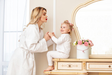 Happy beautiful family mother and daughter at the mirror in the bedroom together