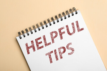 Notebook with phrase Helpful Tips on beige background, top view
