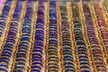 Rows of hairy artificial fly. Profile view. Red-yellow shiny metal heads. Lure concept for used in the sport of fly fishing. Selective focus.
