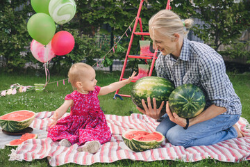 Father and child on a picnic eating big watermelons. Summer family party outdoors with toddler daughter