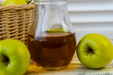 Green apples, basket with apples and jug with apple juice on wooden background