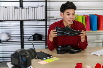 Adult asian seller man look intend holding shoe and looking at camera to present product via live online for shopping online with e-commerce sell
