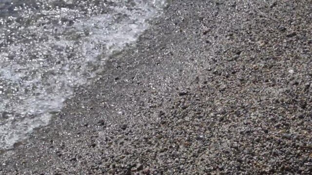 olas cristalinas de lago patagónico rompiendo en una playa con arena gruesa
