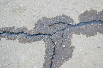 Water flows through cracks in the asphalt. Dry and wet asphalt. The concept of a channel in hard...
