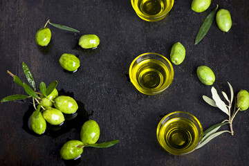 Olive oil and olive branch on black background