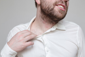 Bearded man does not feel well, he suffocates and tries to widen the collar of his shirt. 