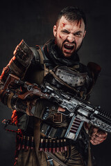 Obraz na płótnie Canvas Apocalyptic and screaming fighter in dark armour holding shotgun