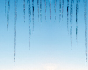 Background of bright transparent icicles in the sunlight. Icicles on the sky background. Copy space. Winter. Nature. World water day