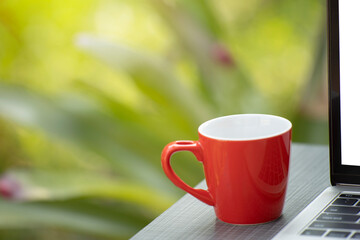 Cup of coffee with laptop in garden