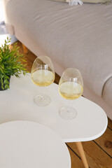 Two glasses of white wine are on the side table