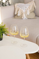 Two glasses of white wine are on the side table