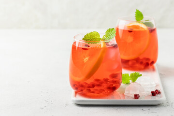 Summer party festive cocktail, iced pomegranate citrus drink in glasses. Space for text.