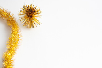 Golden tinsel and Christmas tree toy on a white background, copy space
