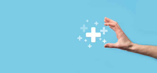 Male hand holding plus icon on blue background. Plus sign virtual means to offer positive thing like benefits, personal development, social network Profit,health insurance, growth concepts