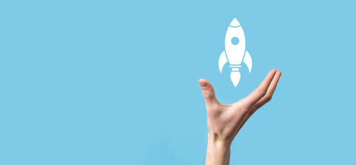 Male hand holding rocket icon that takes off, launch on blue background. rocket is launching and flying out, Business start up, Icon marketing on modern virtual interface.Start up concept.