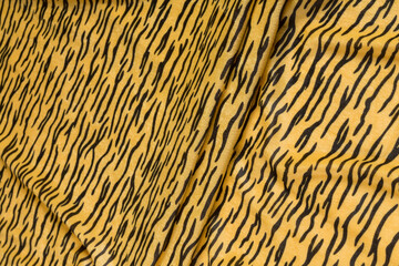 Colored yellow textile satin fabric folded in folds and waves with highlights and texture