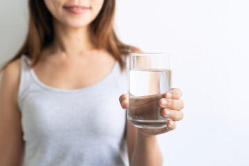 Young Asian woman holding glass of water isolated on white background. Healthy lifestyle concept. Closeup and copy space