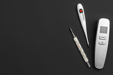 Different type of thermometers on grey background. Infrared, electronic and mercury thermometers. Top view. Space for text.