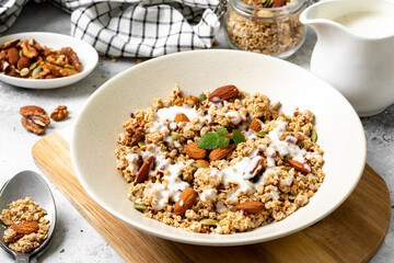Homemade organic nut granola in a ceramic plate on a light background. Baked oatmeal muesli with almonds, walnuts, hazelnuts and pumpkin seeds close-up