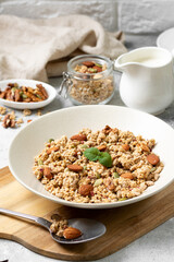 Homemade organic nut granola in a ceramic plate on a light background. Baked oatmeal muesli with almonds, walnuts, hazelnuts and pumpkin seeds close-up
