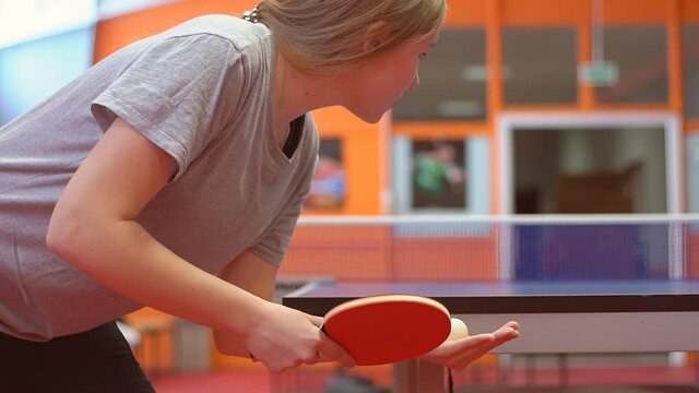 Close up of a female table tennis or ping pong player serving, slow motion