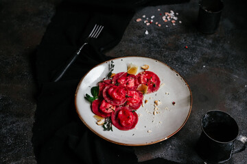 beet ravioli in a light plate on a dark background