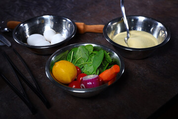 Spinach, onions, eggs and carrots in metal bowls.In a metal dish are ingredients for cooking the dish. Vegetarian ingredients. Vegetable food. Top view.
