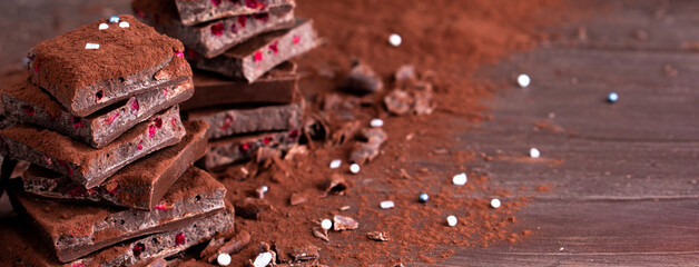 Organic food snack tasty sweet dessert milk dark chocolate bar macro closeup broken slide piece and fruit orange raspberry hazelnut nuts on cocoa cacao powder wooden table for new year Christmas gift
