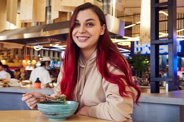 Pretty smiling woman with red hair having lunch in a restaurant.