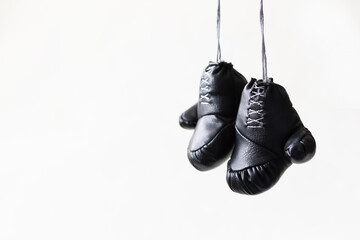 Black boxing gloves hang on a white background.