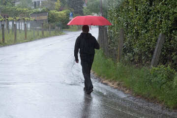 person with a red umbrella walking on the sidewalk