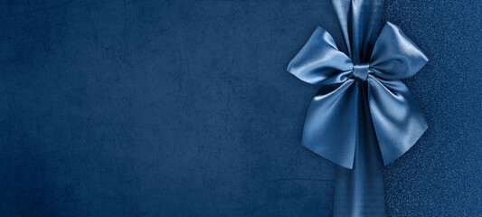 gift card with bright and shiny ribbon bow isolated on blue grunge background, top view and copy...