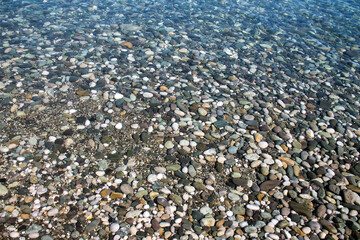 Sea stones in sea water. Pebbles under water. The view from the top. Nautical background. Clean sea water. Transparent sea