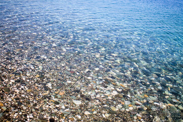 Sea stones in sea water. Pebbles under water. The view from the top. Nautical background. Clean sea water. Transparent sea