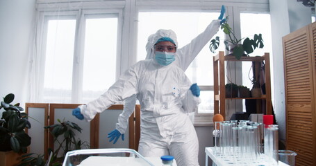 Victory over coronavirus epidemic. Two fun happy female doctors in white protection suits dance celebrating success.
