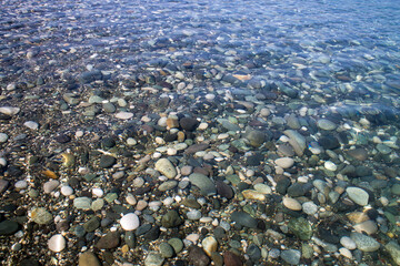 Sea stones in sea water. Pebbles under water. The view from the top. Nautical background. Clean sea water. Transparent sea