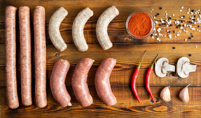 Meat sausages on a wooden table. tomatoes, chili peppers, garlic, mushrooms, spices. Top view.
