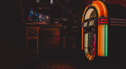 Retro jukebox on dark background in bar - obrazy, fototapety, plakaty