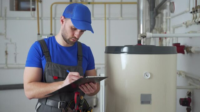 Technician servicing an hot-water heater. Man check equipment of the boiler-house - thermometer. 